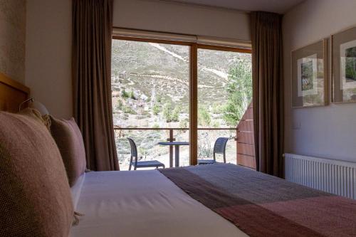 ein Hotelzimmer mit einem Bett und einem großen Fenster in der Unterkunft Lodge El Morado in Refugio Lo Valdés