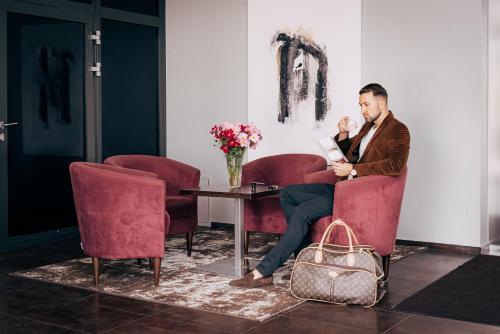 a man sitting in a red chair with a bag at Old Mill Hotel in Klaipėda
