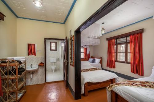 a room with two beds and a bathroom at Gorilla Neighbour Guest House in Entebbe