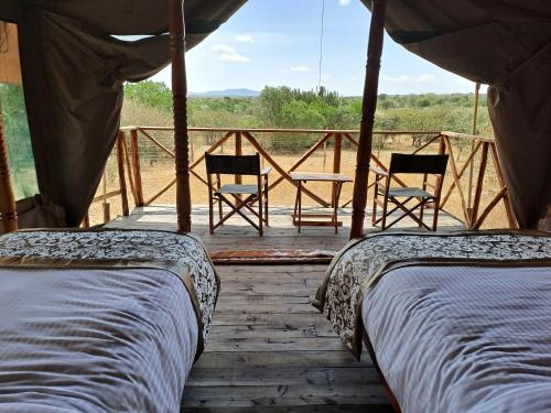 dwa łóżka i dwa krzesła na drewnianym tarasie w obiekcie Tayari Luxury Tented Camp - Mara w mieście Sekenani