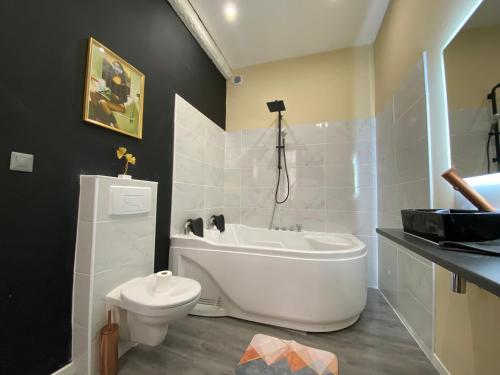 a bathroom with a white tub and a toilet at Baignoire Cosy Centre Narbonne in Narbonne