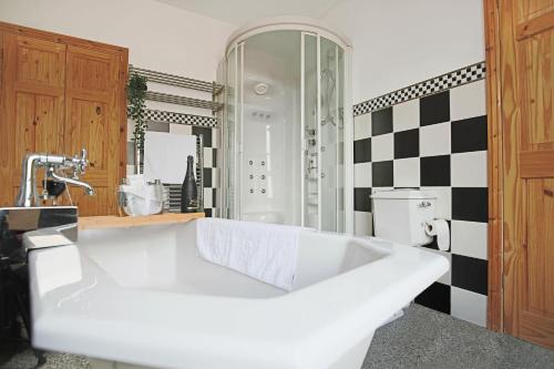 a large white tub in a bathroom with a checkered wall at Spacious House in City Centre - Sleeps up to 9 - Free Parking, Super-Fast Wifi, Garden, Balcony, and Smart TV with Virgin TV and Netflix by Yoko Property in Northampton