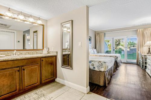 a bedroom with a bed and a sink and a mirror at 255 Sandcastles in Fernandina Beach