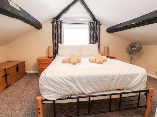a bedroom with a large white bed with a window at Scotch Hall Cottage in Llangollen