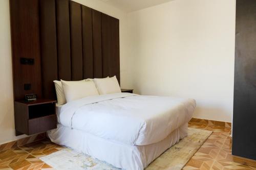 a bedroom with a large white bed with a wooden headboard at Jotani Living in Lagos