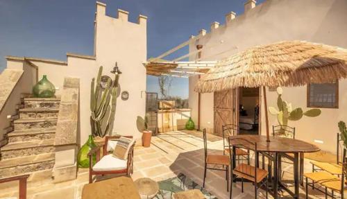 eine Terrasse mit einem Tisch und einem großen Sonnenschirm in der Unterkunft Masseria li Vecchi in Squinzano