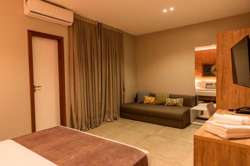 a living room with a couch and a television at Bravo Pousada Design in Cabo Frio
