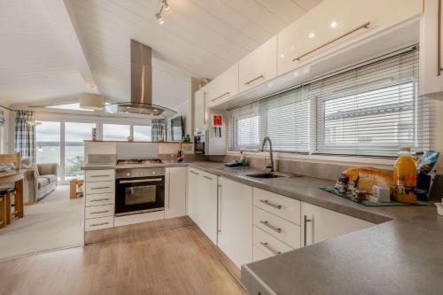 uma grande cozinha com armários brancos e uma grande janela em Bay Hollow em Poole