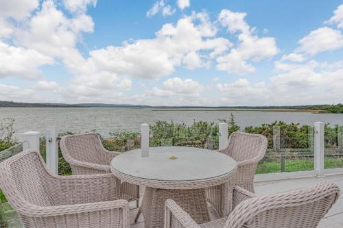 a table and chairs on a patio with a view of the water at Bay Hollow in Poole