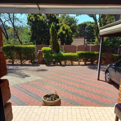 a brick driveway with a pot of flowers in a yard at Lime Court Four in Pretoria