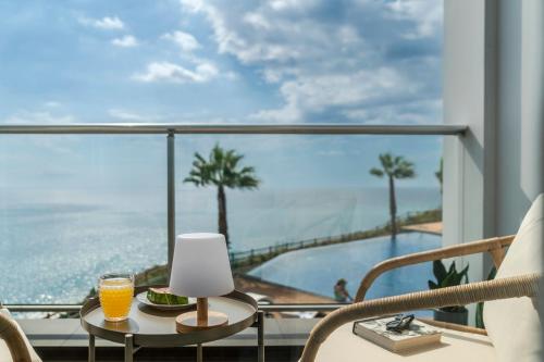 un tavolo con un bicchiere di succo d'arancia su un balcone con vista di Madeira Palace III by An Island Apart a Funchal