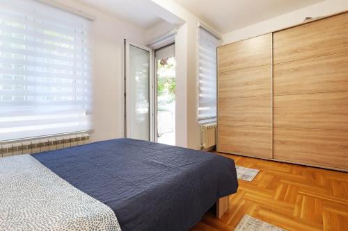 una camera con letto blu e armadi in legno di Lion Apartment - Belgrade a Belgrado
