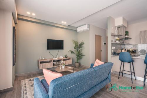 a living room with a blue couch and a tv at Chic Fully Serviced Apartment at Regatta Living II - 705 in Los Prados
