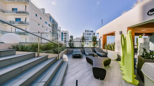 a balcony with couches and chairs on a building at Chic Fully Serviced Apartment at Regatta Living II - 705 in Los Prados