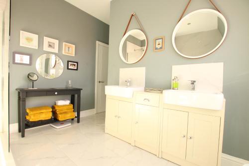 a bathroom with two sinks and two mirrors at Lovely, cosy 3 bedroom apartment in Teddington