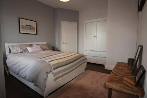 Lovely, cosy 3 bedroom apartment في تدينغتون: غرفة نوم بسرير كبير وطاولة
