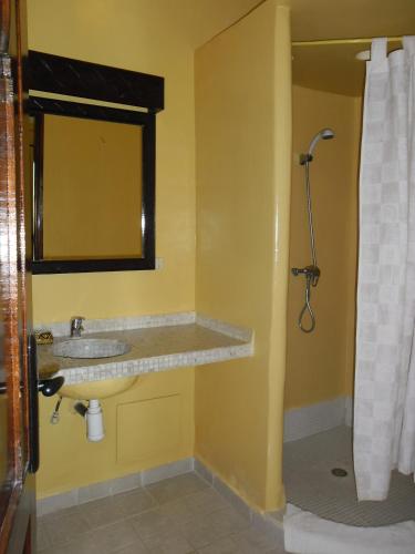 a yellow bathroom with a sink and a shower at Riad Zahra in Essaouira