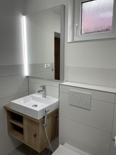 een witte badkamer met een wastafel en een spiegel bij Smart Apartment l in Huncovce