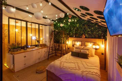 - une chambre avec un grand lit recouvert de plantes dans l'établissement Love Room Romantique Les Petits Plaisirs, à Angers