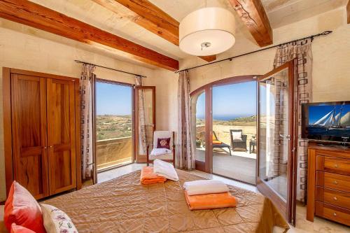 Schlafzimmer mit einem Bett, einem TV und Fenstern in der Unterkunft Dream by Hamlet Holiday Home in Għasri