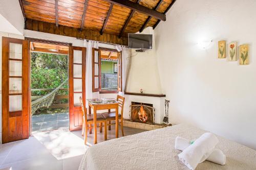 a bedroom with a bed and a table and a fireplace at Pousada Alto de Monte Verde in Monte Verde