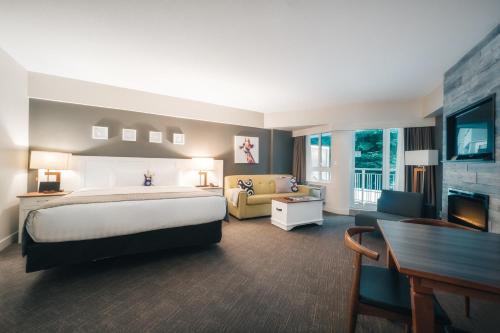 a large hotel room with a bed and a couch at Summit Lodge Boutique Hotel Whistler in Whistler