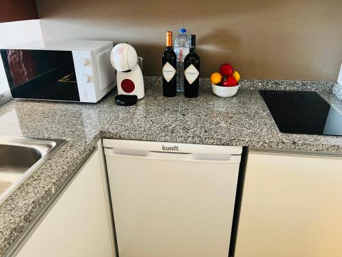 a kitchen counter with bottles of wine and a microwave at Sunset Lover Aparthotel Guadiana in Monte Gordo