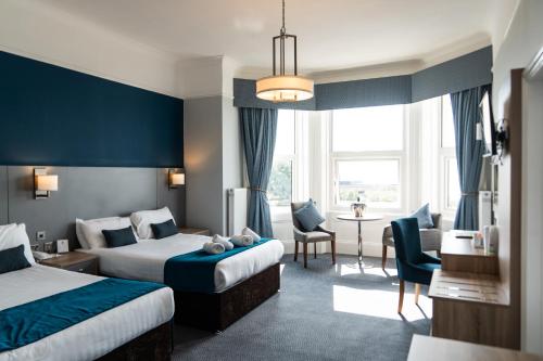 イーストボーンにあるThe Lansdowne, Eastbourneのベッド2台、テーブルと椅子が備わるホテルルームです。