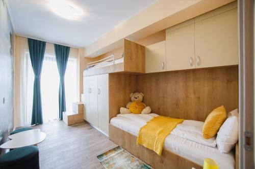 um quarto com um urso de peluche sentado numa cama em Grand Panorama City Views em Oradea