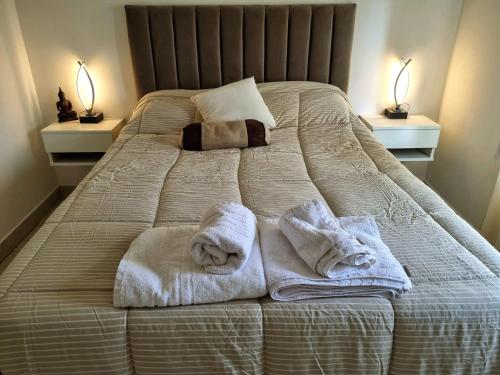 a bed with towels on it with two lamps at Paraná Confort in Paraná