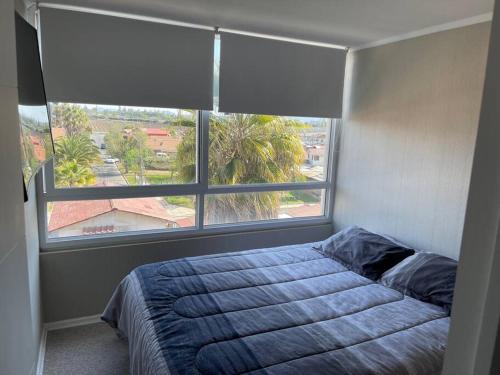 a bedroom with a bed and a large window at Hermoso Depto Piscina Quincho in Rancagua