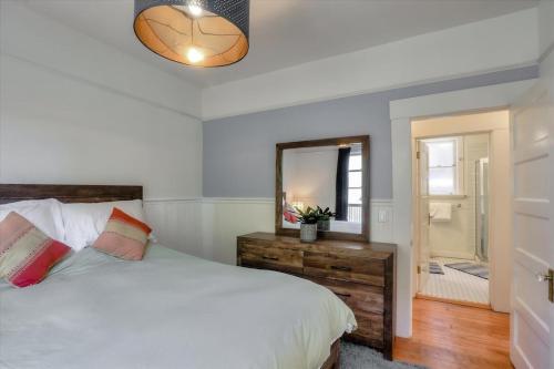 Schlafzimmer mit einem weißen Bett und einem Spiegel in der Unterkunft Light filled Condo with enclosed sunny backyard in Oakland