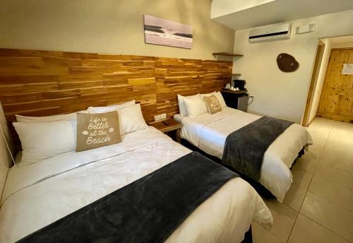 a hotel room with two beds and a wooden wall at Hotel El Manglar in Playa Grande
