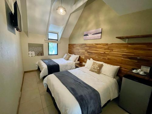 a bedroom with two beds and a wooden wall at Hotel El Manglar in Playa Grande