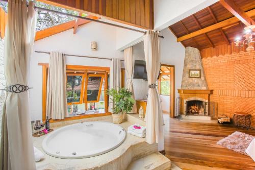 a bathroom with a large tub and a fireplace at Pousada Alto de Monte Verde in Monte Verde