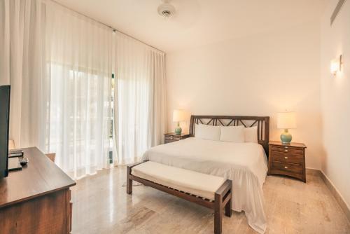 a white bedroom with a bed and a window at Go away to this charming apt at Sublime w private jacuzzi included in Las Terrenas