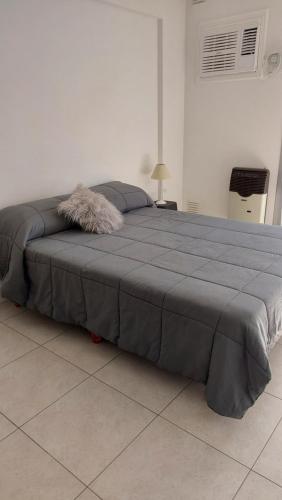 a large bed in a white room with a blue blanket at Bahía Rental-Departamento x dia in Bahía Blanca