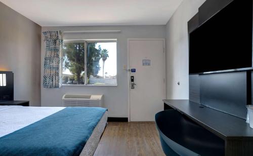 a bedroom with a bed and a flat screen tv at Motel 6-Bakersfield, CA - South in Bakersfield