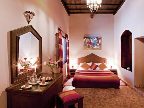 a bedroom with a bed and a large mirror at Riad Maison Du Sud in Essaouira