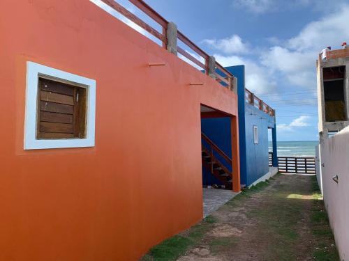 an orange and blue building next to the ocean at Chalés Solmar in Itapipoca