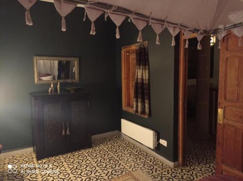 a room with a dark green wall with a table and a mirror at Riad Dar Badiaa in Sale
