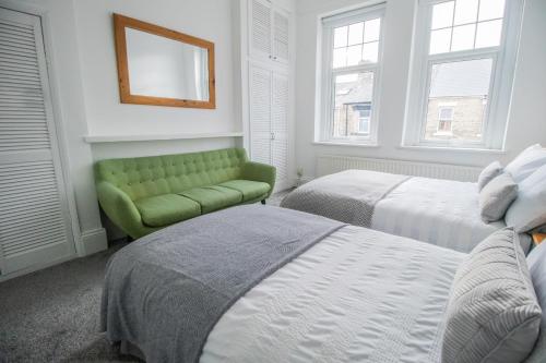 a bedroom with two beds and a green couch at Dwellcome Home Ltd 2 Bedroom 3 Bed South Shields Apartment - see our site for assurance in South Shields