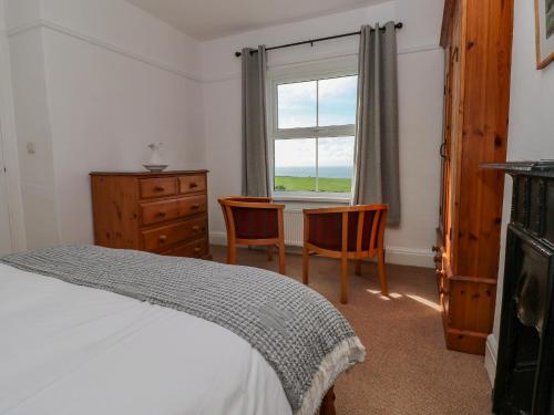 a bedroom with a bed and two chairs and a window at Bay View Farmhouse in Haverfordwest