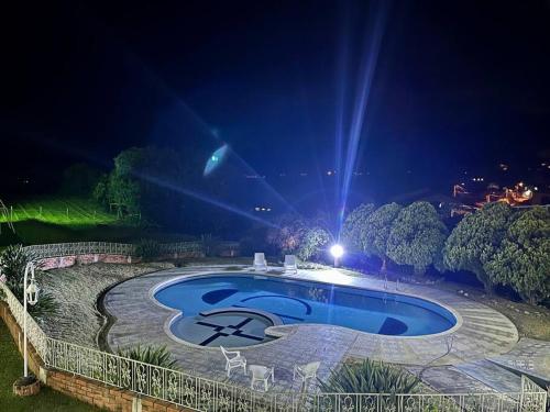a swimming pool at night with chairs around it at Finca tres colinas in Lemos