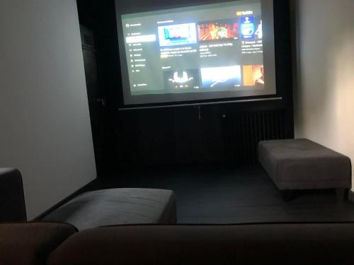 Cette chambre dispose d'un grand écran avec un canapé et un tabouret. dans l'établissement Paradis Du Nord, à Wallers
