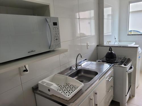 eine Küche mit einer Spüle und einer Mikrowelle in der Unterkunft Apartamento completo no centro de Tijucas 105 in Tijucas
