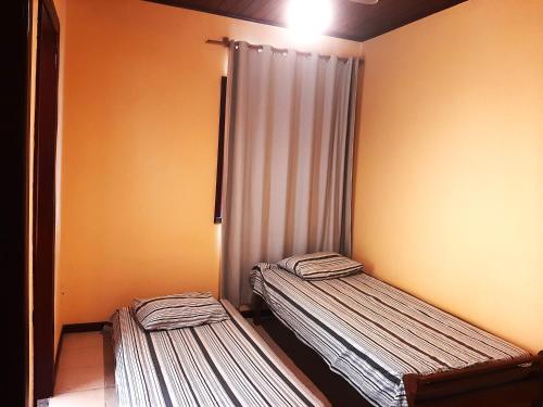 two beds in a small room with a curtain at Village Praia do Flamengo frente mar in Salvador