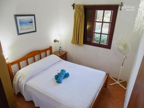 a blue teddy bear sitting on a bed at Cabañas Dunas del Diablo in Punta Del Diablo
