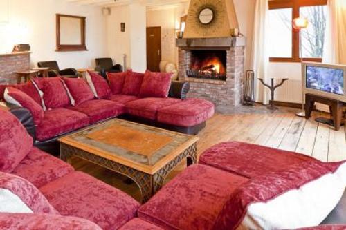 a living room with red furniture and a fireplace at Par Hasard in Maffe