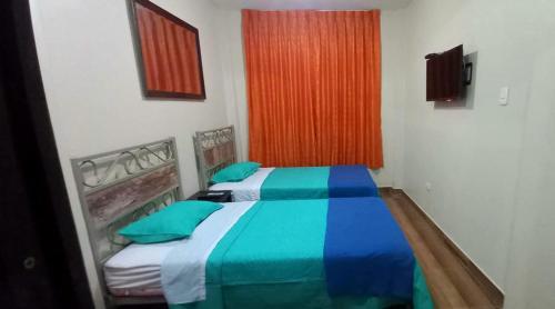 1 Schlafzimmer mit 2 Betten mit blauer und grüner Bettwäsche in der Unterkunft Diamond Monkey Lodge in Ica